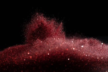 Patlama metalik kırmızı parıltı parıltısı. Gül tozu tozu kıvılcımı kutlama, bulanık folyo havada patlar, sinek kırmızı parıltı parçacığı fırlatır. Siyah arkaplan izole, seçici odak Görüntü bokeh