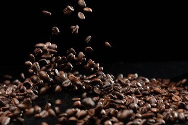 Coffee roasted bean fly explosion, Coffee crushed float pouring mix with beans. Roasted Coffee bean splash explosion in mid Air. Black background Isolated selective focus blur