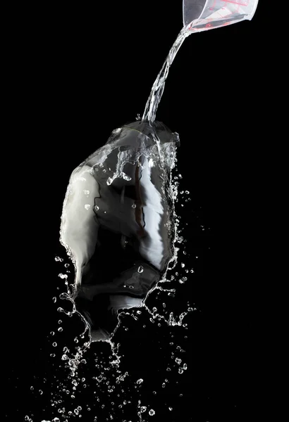 Pouring Water on pants object to create shape form splash fluttering in droplet and wave. Pouring water to object make curve drop splash in directions. Black background isolated