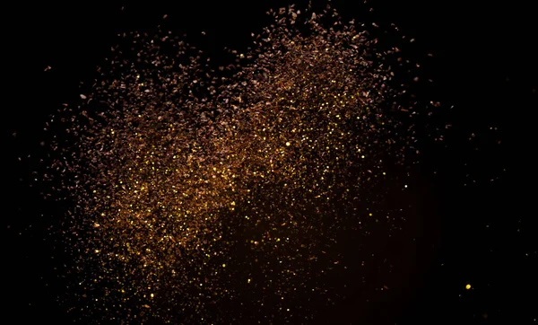 Ground Coffee roasted powder dust fly explosion, Coffee crushed ground float pouring. Roasted Coffee powder ground dust splash explosion in mid Air. Black background Isolated gold bokeh