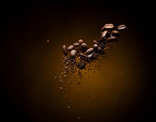 Coffee roasted bean ground fly explosion, Coffee crushed ground float pouring mix with beans. Roasted Coffee bean powder ground dust splash explosion in mid Air. Black background Isolated gold bokeh