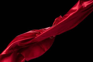 Kırmızı saten kumaş kıvrımlı uçuyor, kırmızı saten kumaş parçası havaya düşüyor. Siyah arkaplan izole hareket bulanıklığı