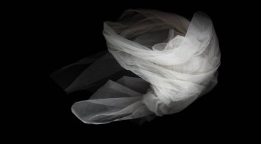 Eğri şeklinde uçan beyaz organza dantel kumaş, beyaz organza dantel kumaş parçası havaya düştü. Siyah arkaplan izole, koyu gölgeleme ortamı