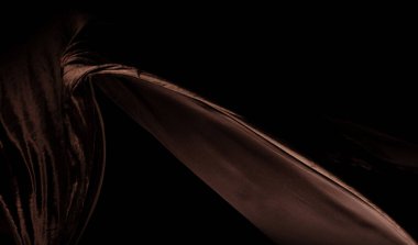 Kahverengi kadife kumaşın kıvrımlı uçtuğunu hissetti. Tekstil kahverengi kadife parçasının kumaşın havaya düştüğünü hissetti. Siyah arkaplan izole, koyu gölgeleme ortamı