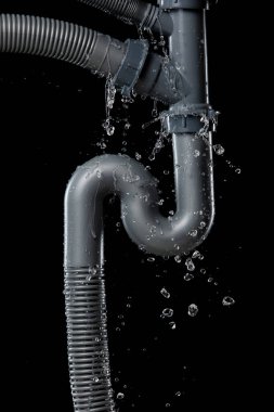 Lavabonun altındaki gri plastik borudan su sızdırıyor. Banyodaki borulardan su sızıyor ve su tıkanmış. Siyah arkaplan izole