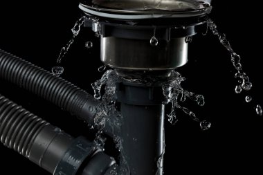Tuvaletteki boru tesisatından sızan lavabo suyu damlaları tıkadı. Gri plastik boru lavabosundan sızan su. Siyah arkaplan izole