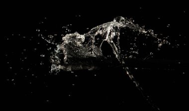 Crown sudan nesneye dalgalı hareketle kavisli düşüş patlaması yapıyor. Siyah arka plan izole. Crown Water damlacıklar ve dalgalar halinde çırpınan şekil yaratmak için nesnenin üzerine su sıçrar.. 