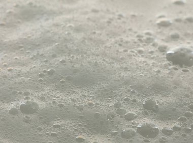 Yüzeydeki sabun banyosu şampuan jelinden köpükler çıkıyor. Kabarık banyo köpüğü ya da yüzey dalga eğrisi dokusunda bira köpüğü köpüğü kabarcık oluşturur.