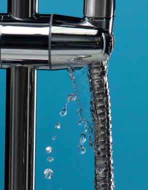 Su tıkandığı sırada banyodaki su borularından bidet duşu başlığı suyu sızıyor. Mavi banyo arka planı izole edildi. Krom, paslanmaz çelik bide duş başlığından su sızdırıyor.