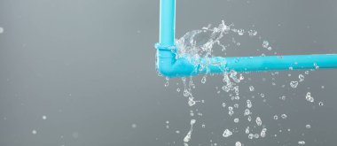 Lavabonun altındaki mavi plastik borudan su sızdırıyor. Mavi PVC plastik borudan sızan su banyodaki su tesisatını bozdu. Gri arkaplan izole