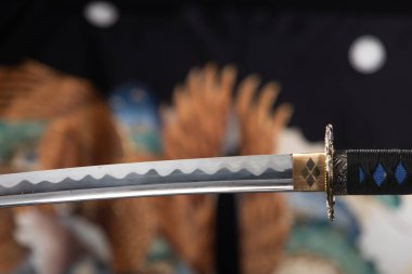 Japon katana samuray kılıcı Kimono 'nun arka planında havada asılı duruyor. Katana samuraylarının keskin kılıcı Japon dövüş sanatlarının silahıdır.