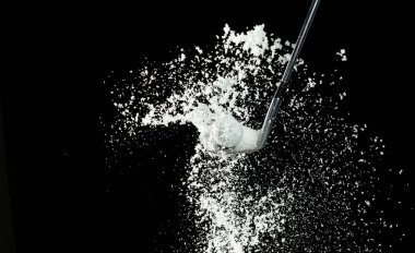 Golf Ball golfer hit snow to explode and splatter. Sand wedge golf dick ball from snow field and snow fly in air. Night black background isolated