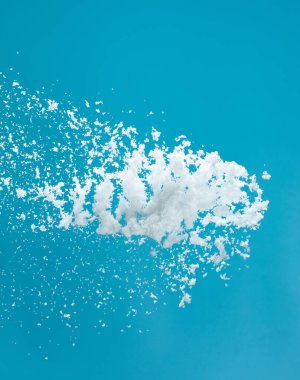 Mavi gökyüzüne düşen kar tozu elementi. Kabarık beyaz kar, havada süzülüyor ya da havada süzülüyor. Mavi arkaplanda kar yağışı izole edildi