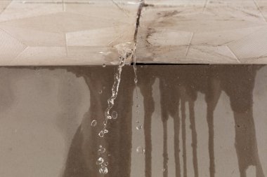 Şiddetli fırtına yağmuru tavandan su akışını ve duvardaki kirli lekeyi oluşturur. Eski evin tavanından damlacıklar gibi su sızıyor.