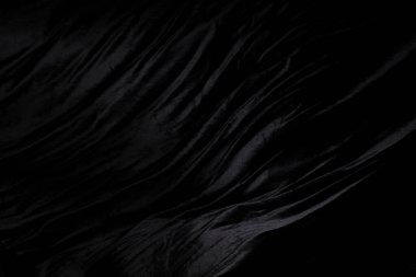 Siyah kadife kumaşın kıvrımlı uçtuğunu hissetti. Tekstil siyah kadife parçası kumaşın havaya düştüğünü hissetti. Siyah arkaplan izole, koyu gölgeleme ortamı