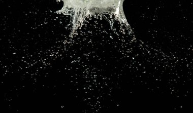 Crown sudan nesneye dalgalı hareketle kavisli düşüş patlaması yapıyor. Siyah arka plan izole. Crown Water damlacıklar ve dalgalar halinde çırpınan şekil yaratmak için nesnenin üzerine su sıçrar.. 