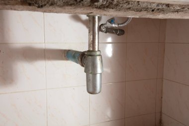 Lavabonun altındaki su borusunda sızıntı var, kanalizasyon tıkanmış. Su borunun etrafında sızıyor çünkü lavabo yavaş yavaş boşalıyor ve evde su sıçrıyor, yüksek hızlı deklanşör dondurucu hareketli fotoğraf.