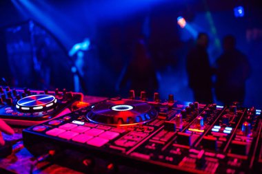 DJ konsolu müziği karıştırıyor bulanık insanlar gece kulübü partisinde dans ediyor