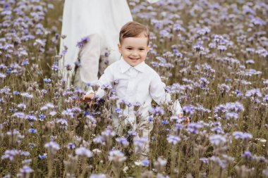 Gülümseyen mutlu çocuk çiçek açan tarlada koşar