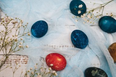 Easter eggs, small white flowers and decorations on a light background. Happy easter flat lay concept.