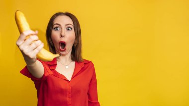 Muzlu komik surat. Gülümseyen genç bir kadın elinde bir muz tutuyor. Komik ifadeler. Beslenme kavramı. Taze muz. Sarı stil. Vitaminler. Metnin için boş alan