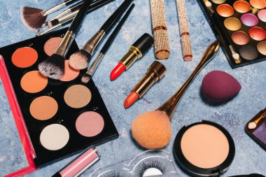 Dekoratif kozmetik ürünleri, makyaj fırçaları takma kirpikler mavi arka plan. tepeden görünüm