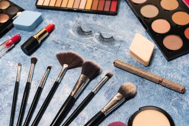 Dekoratif kozmetik ürünleri, makyaj fırçaları takma kirpikler mavi arka plan. Yukarıdan görünüm