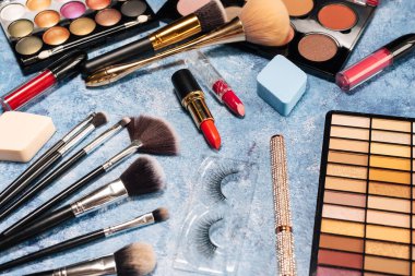 Dekoratif kozmetik ürünleri, makyaj fırçaları takma kirpikler mavi arka plan. tepeden görünüm