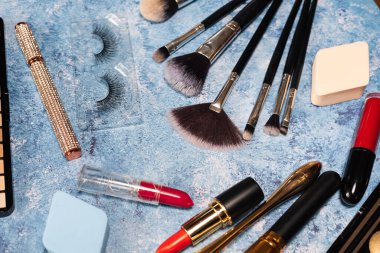 Dekoratif kozmetik ürünleri, makyaj fırçaları mavi arka plan. tepeden görünüm