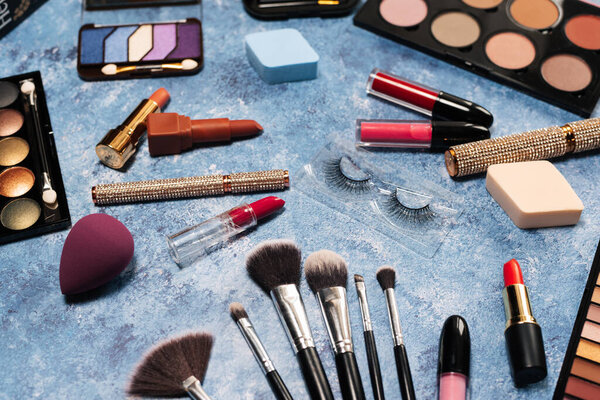 makeup brushes, decorative cosmetics, false eyelashes blue background. the view from the top