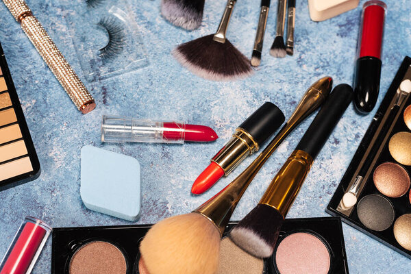 set decorative cosmetics, makeup brushes blue background. view from top