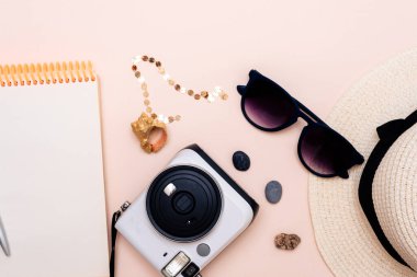 Yaz seyahati aksesuarları. Kamera, şapka, gözlük ve düz bir Notepad üst görünümü düz ışık arkaplanı yatıyordu