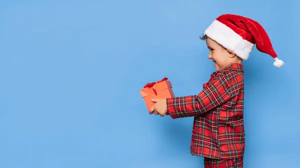 Ein Lächelnder Kleiner Junge Weihnachtlichem Schlafanzug Und Hut Mit Geschenkbox Stockbild
