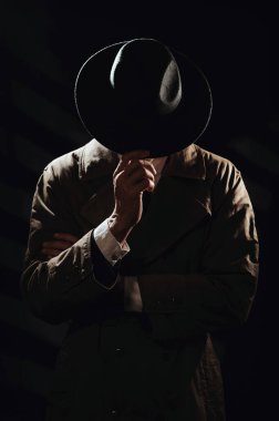 Siyah bir siluet. Palto ve şapkalı bir adamın yüzünden. 1950 ve 60 'ların dedektif filmleri ve casusluk kitaplarının dramatik bir portresi.