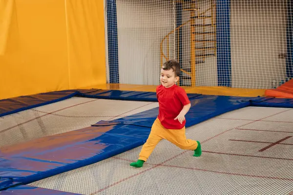 A happy boy runs and jumps on a trampoline in an entertainment center. Childhood. Active leisure