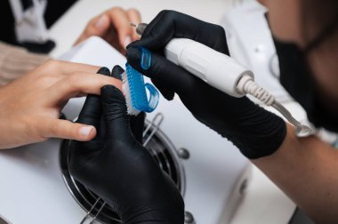 Donanım manikürü. Manikür ustasının yakın plan fotoğrafı. Jel cilasını tırnak makası ile törpülüyor.