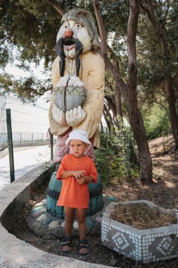 Küçük bir çocuk parkta yürüyor. Ailesiyle birlikte bir çocuk yerel gösterileri, bahçe figürlerini ve heykelleri keşfediyor.