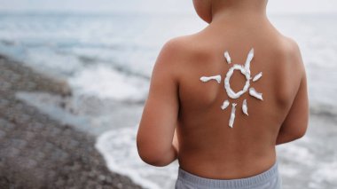 Güneş kreminden yapılmış güneş kremi desenli bir erkek omzunun yakın çekimi. Bebek derisi hakkında koruma