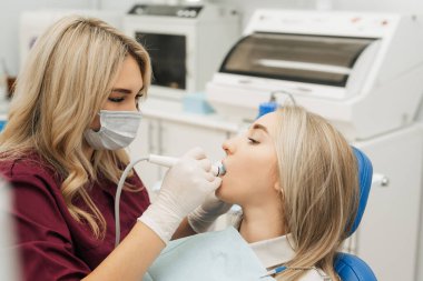 Dişçi, dişinin ağzının tartarını temizlemek için rutin bir ameliyata başlar.