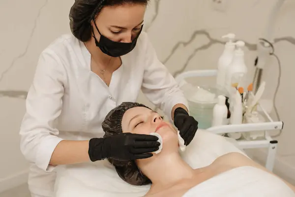 Der Kosmetiker Reinigt Die Haut Des Kunden Mit Wattepads lizenzfreie Stockfotos