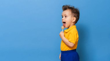 Lolipopu olan bebek mavi duvar arkasında duruyor. Çocukluk kariyerlerinin önlenmesi. Boşluğu kopyala