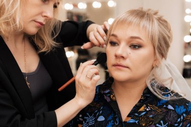 Makyöz, modelin cildine allık sürmek için fırça kullanır.