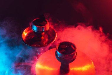 Nargile kasesi, shisha ve kömür dumanlı siyah arka planda yakın plan renkli ışıklandırma