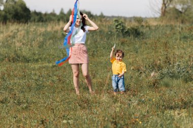 Anne ve oğlu açık alanda uçurtmayla oynuyorlar.