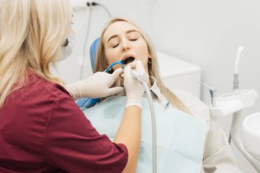 Bir dişçi dişçiye dişlerini tıbbi bir matkapla deldirir.