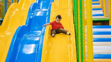 Oyun eğlence merkezindeki çocuk parkında kayan bir çocuk var. Aktif boş zaman. Çocukluk ve neşe