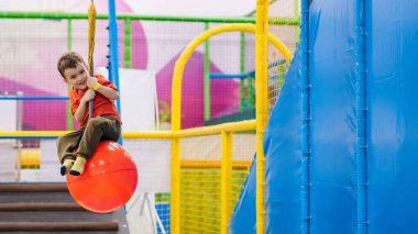 Neşeli küçük bir çocuk oyun parkındaki çocuk eğlence merkezinde oynuyor.