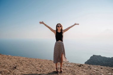 A young woman with her hands up in the fresh air against the background of the sea