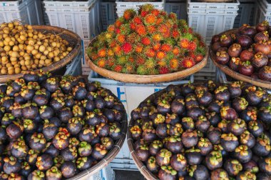 Mangosteen and rambutan are sold in wicker baskets in the Asian market of Nha Trang, Vietnam. clipart