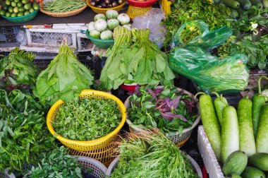 Markette sepetler içinde çeşitli sebze ve otlar var. Asya sebzeleri. Vietnam Pazarı